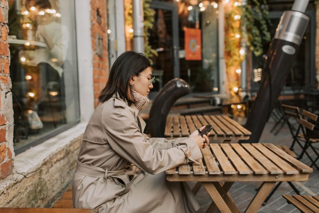 Man bekijkt telefoon en notitieboekje op een cafétable om zijn avond te plannen