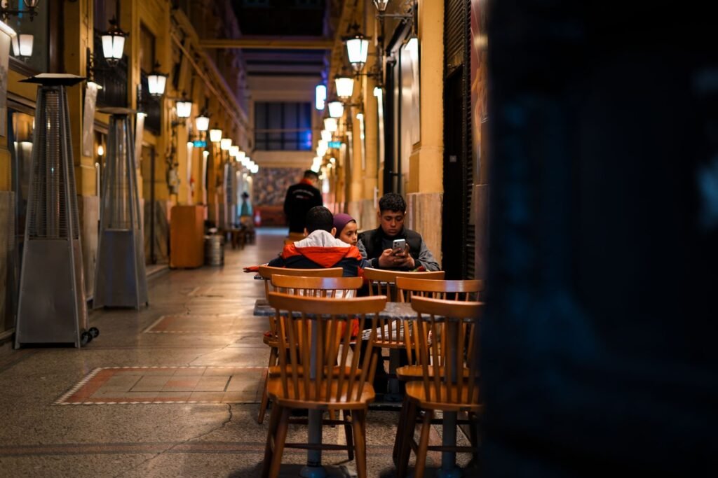 Twee volwassenen in gesprek aan een cafΓ©table in de avond
