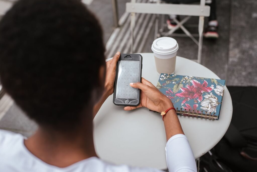 Personne rédigeant un message courtois sur son téléphone dans un café lumineux