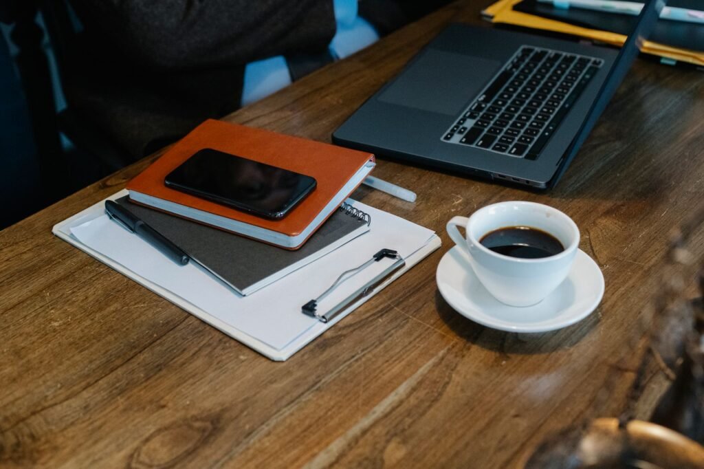 Smartphone en notitieboek op een houten tafel bij een kop koffie, symbool voor het rustig bekijken van een escortprofiel