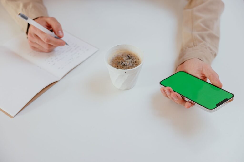 Handen met smartphone en notitieboek op een houten tafel