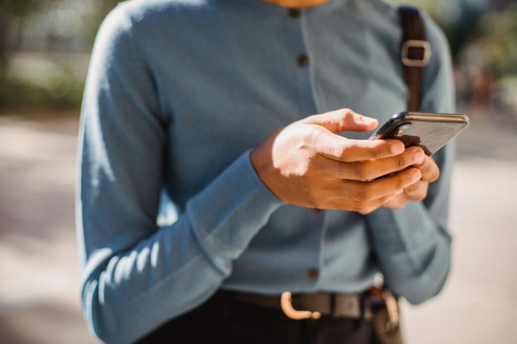 Handen die een kort bericht typen op een smartphone bij een raam, passend bij het onderdeel over respectvol contact leggen