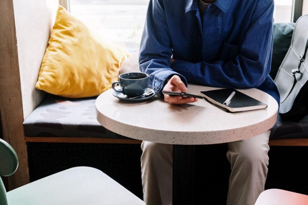 Iemand plant een afspraak met smartphone en notitieboek in een café