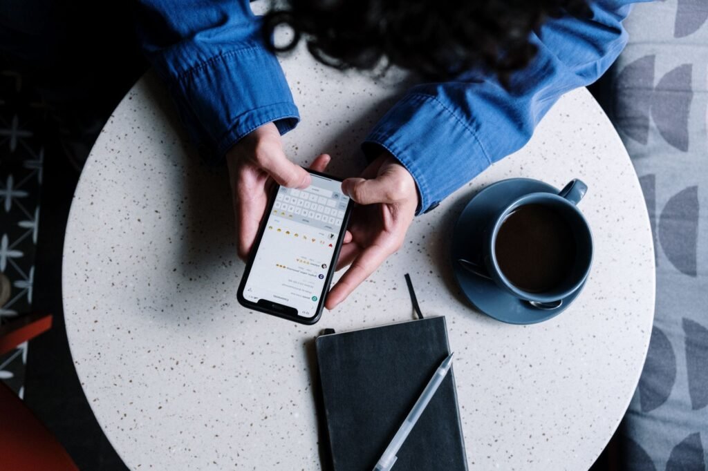 Smartphone met berichtenapp op een houten cafetafel naast een koffiekopje