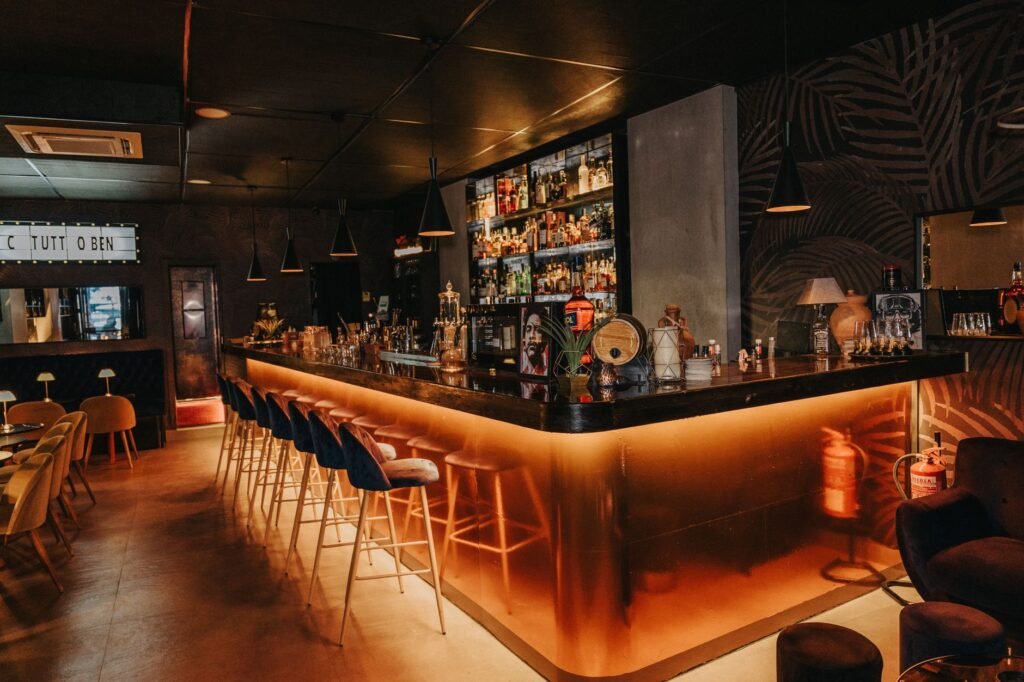 Intérieur d'un bar lounge tamisé en soirée, ambiance adulte discrète
