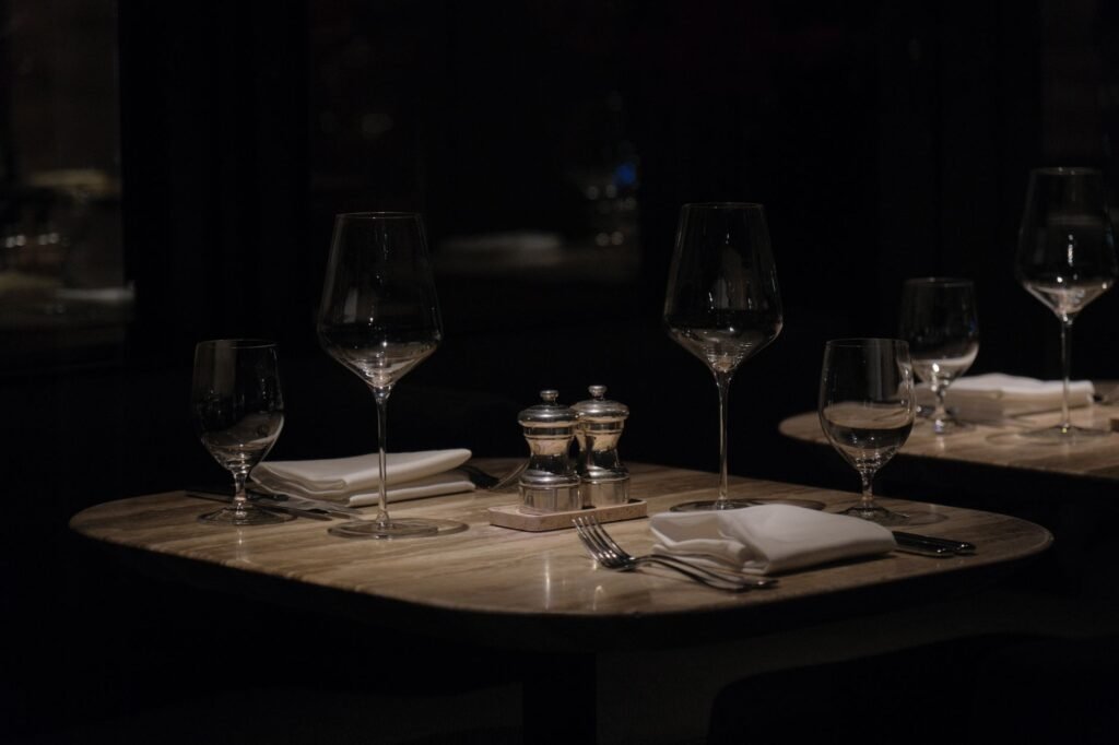 Table dressée pour deux dans un intérieur de restaurant belge le soir, lumière tamisée et atmosphère intime