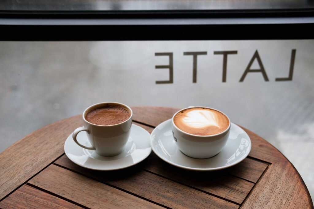 Twee koffiekopjes op een tafel bij een raam in een Belgisch café